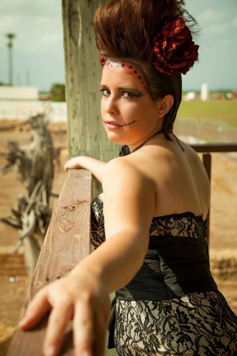 Gothic romance style portrait in lace dress with red flower hair accessory.