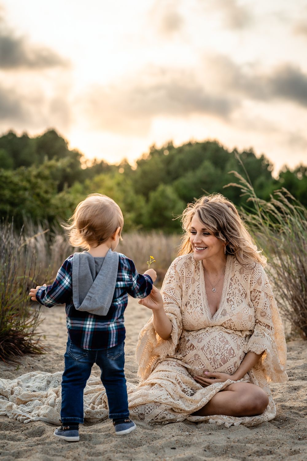 A sweet moment between mother and toddler playing on a sandy beach at sunset.