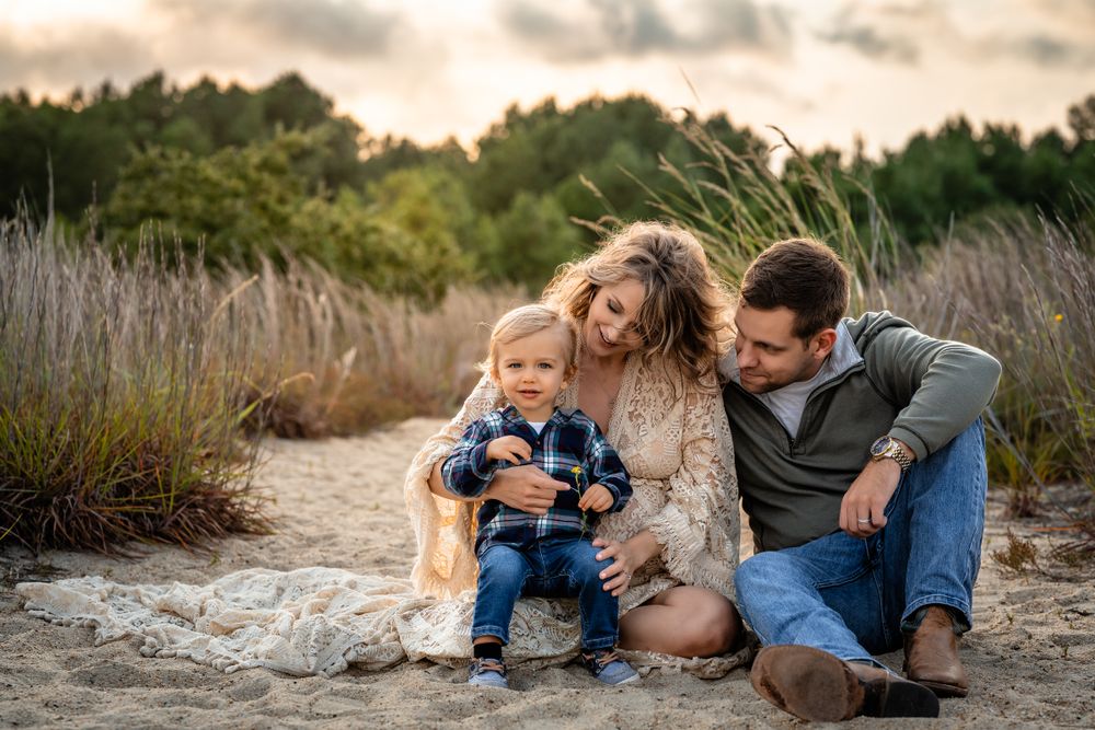 A casual family moment captured on a sandy path with pine trees in background.