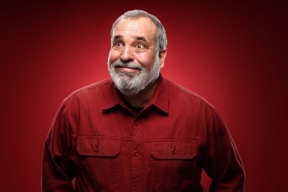 Portrait of someone in a red shirt expressing joy against red background.