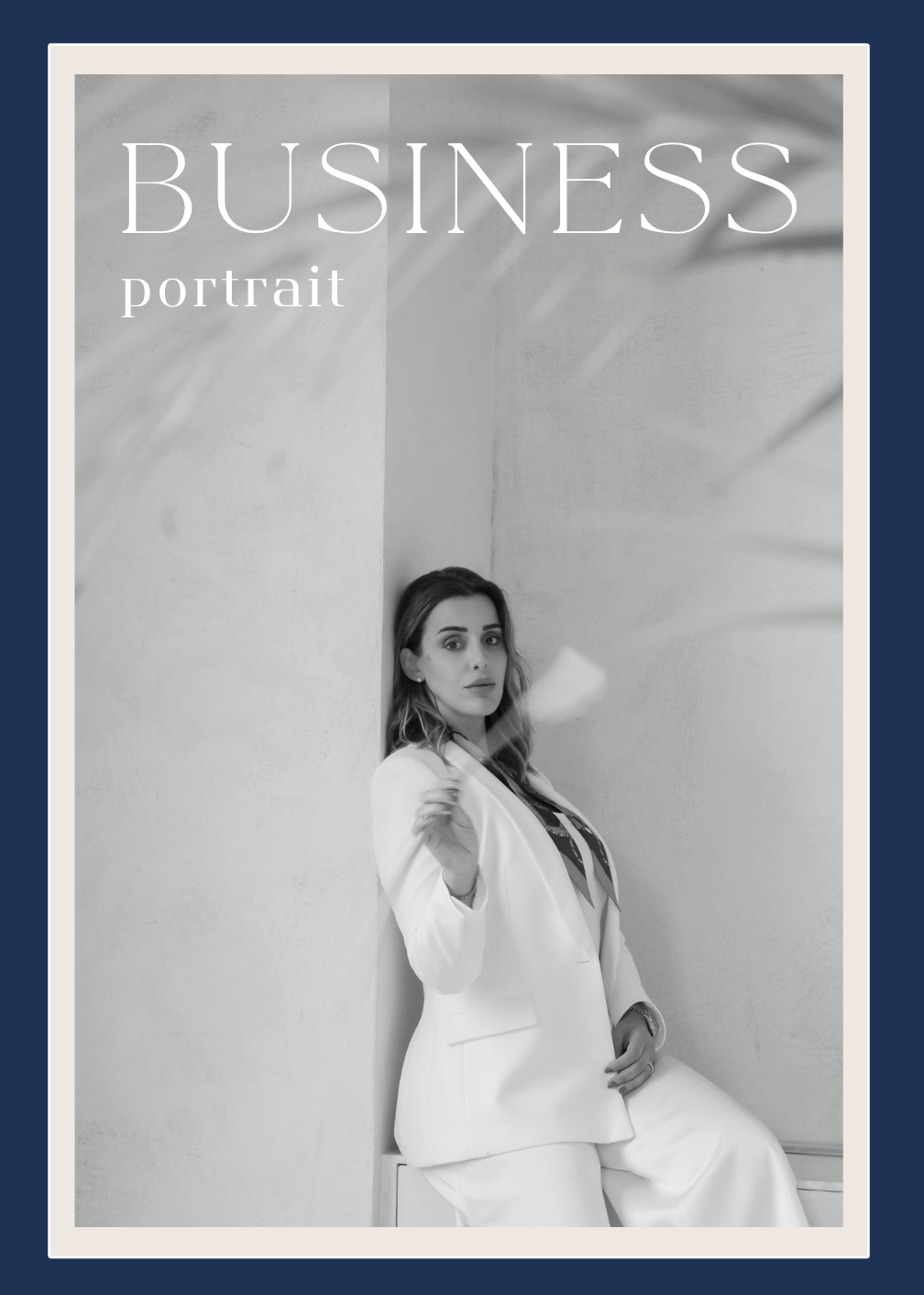 Professional wearing a navy blazer smiles warmly while resting hands under chin in business portrait.