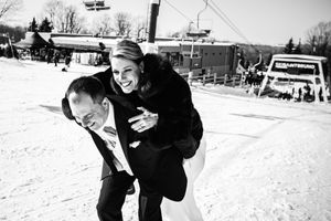Photo en noir et blanc d’un couple de nouveaux mariés souriant et jouant dans la neige à la station de ski Saint-Bruno.