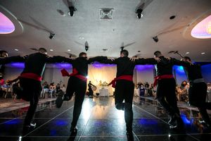 Durant un mariage, une troupe de danse traditionnelle moyen-orientale est vue de dos en train de performer devant les nouveaux mariés.