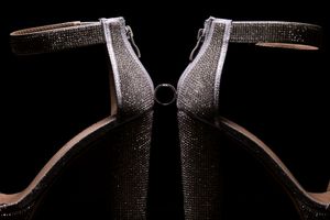 Photo en gros plan d’une alliance de mariage en équilibre entre deux souliers à talon haut brillants avec un éclairage dramatique.
