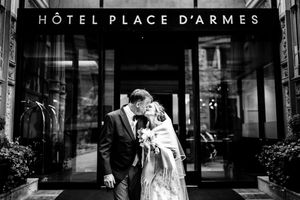 Photo en noir et blanc d'un couple s'embrassant devant l'hôtel Place d'Armes à Montréal le jour de leur mariage.