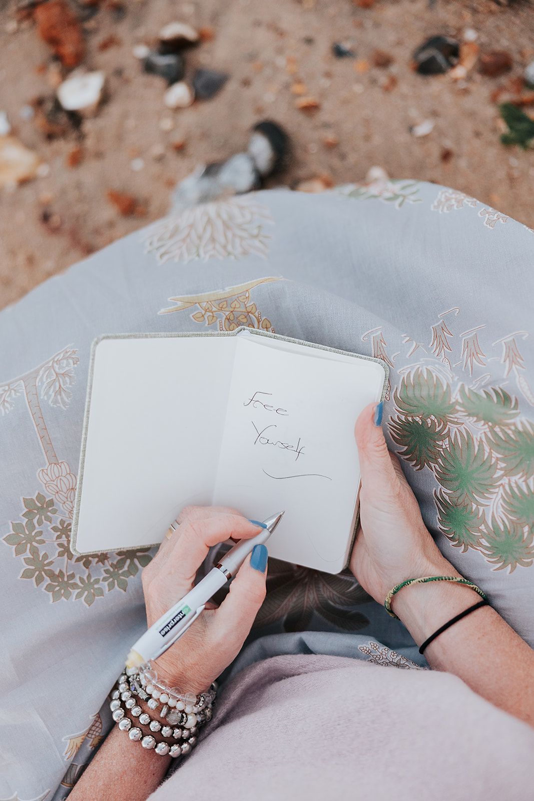 Hands holding a pen and writing on white paper with decorative gold floral patterns around the edges.