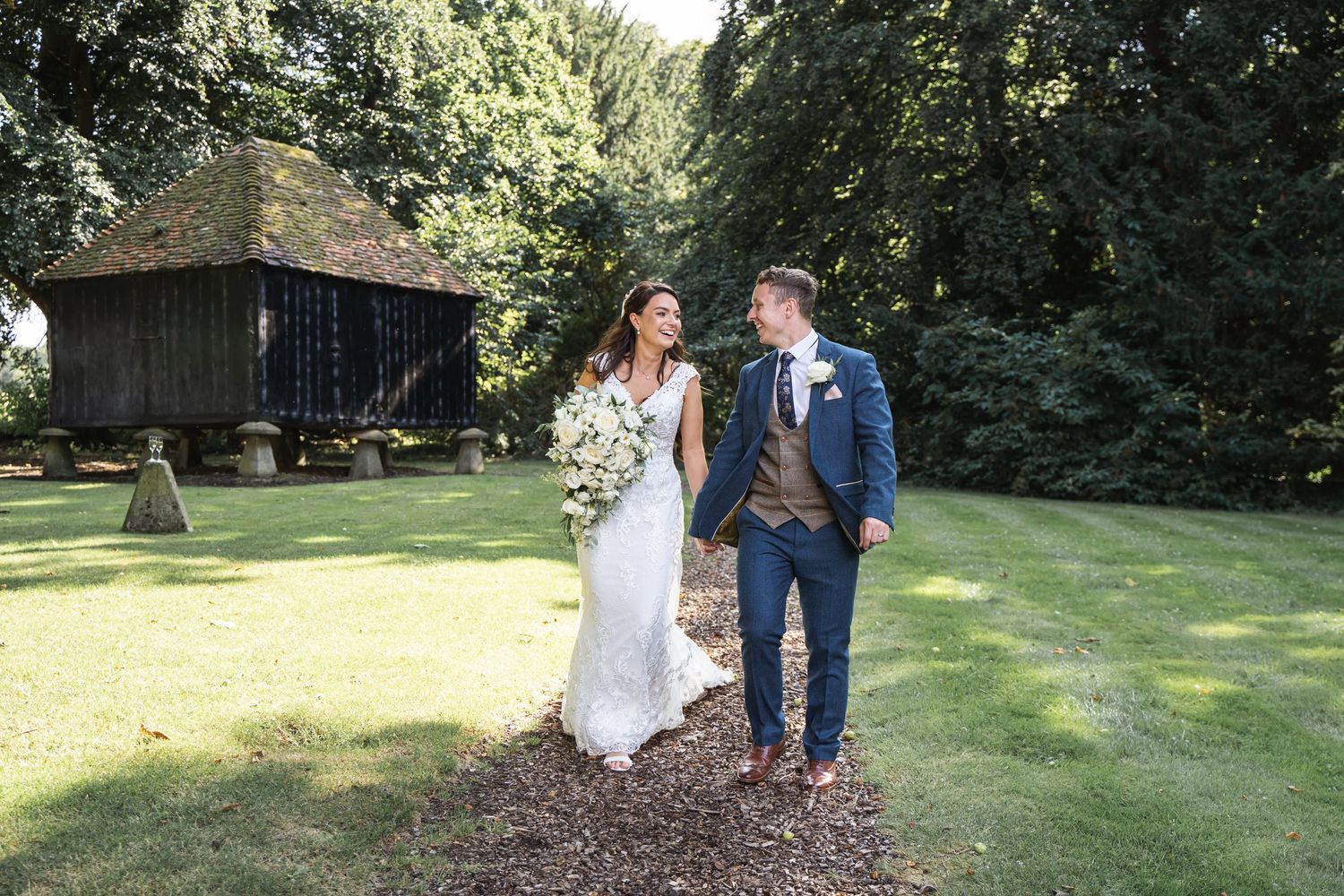 Lains Barn Wedding Photography Bride & Groom walking next to the grain store