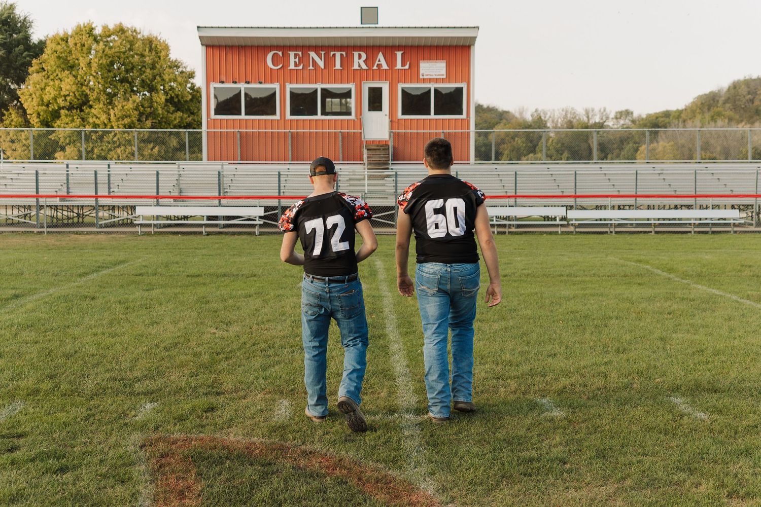 Wide view of Central school building and football field with players in distance.