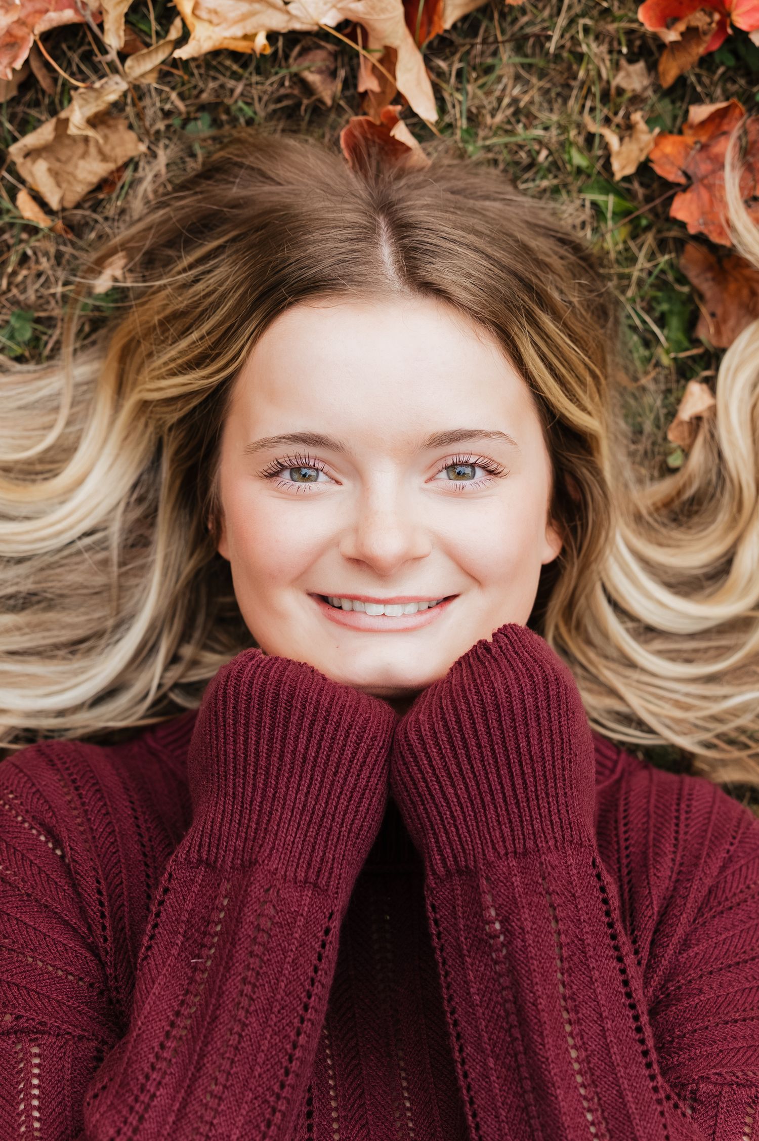 A series of four photos showing a cozy autumn portrait with a burgundy sweater and fall leaves in the background.