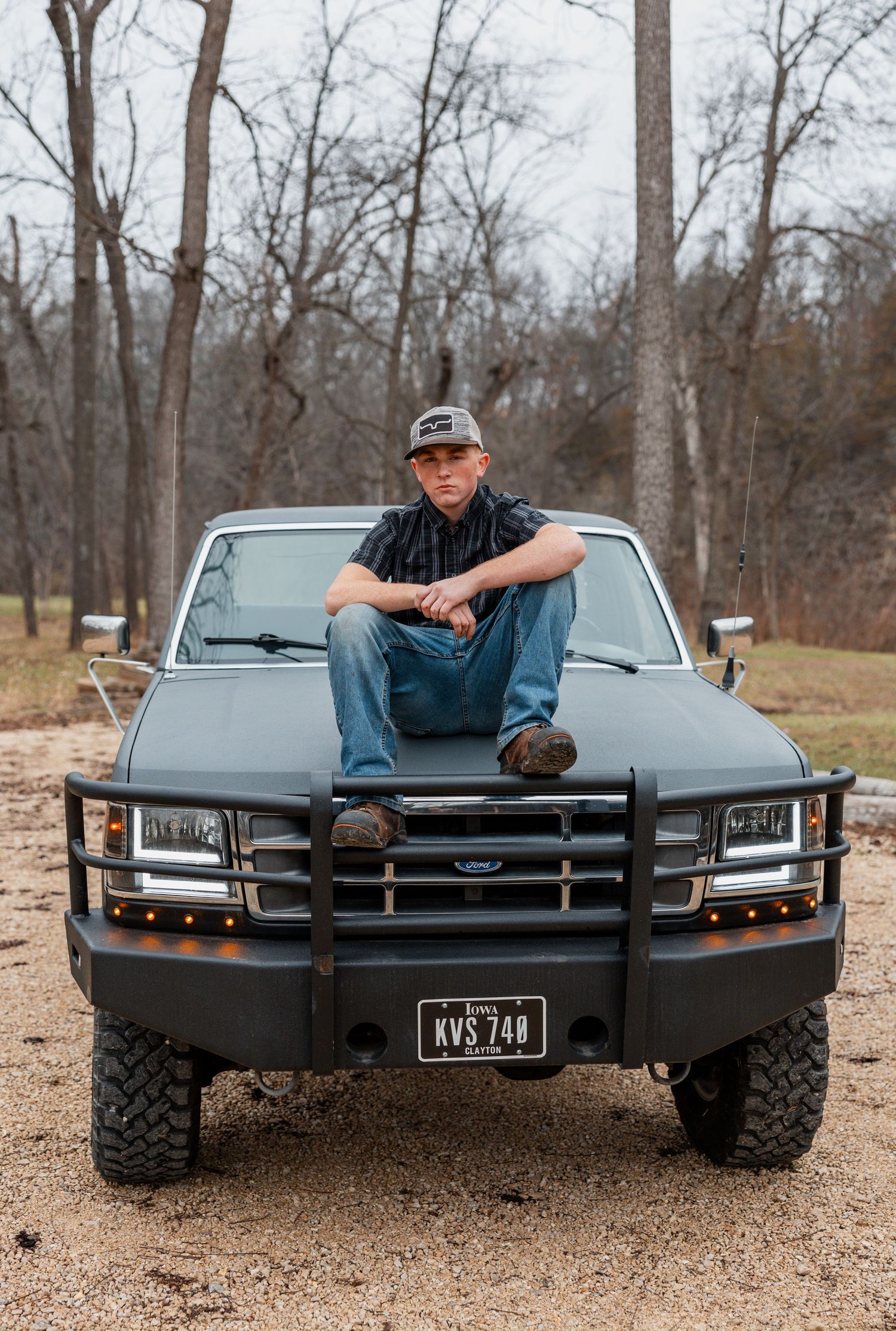Three views of a customized black Chevrolet Corvette with off-road modifications parked on gravel in a wooded area.