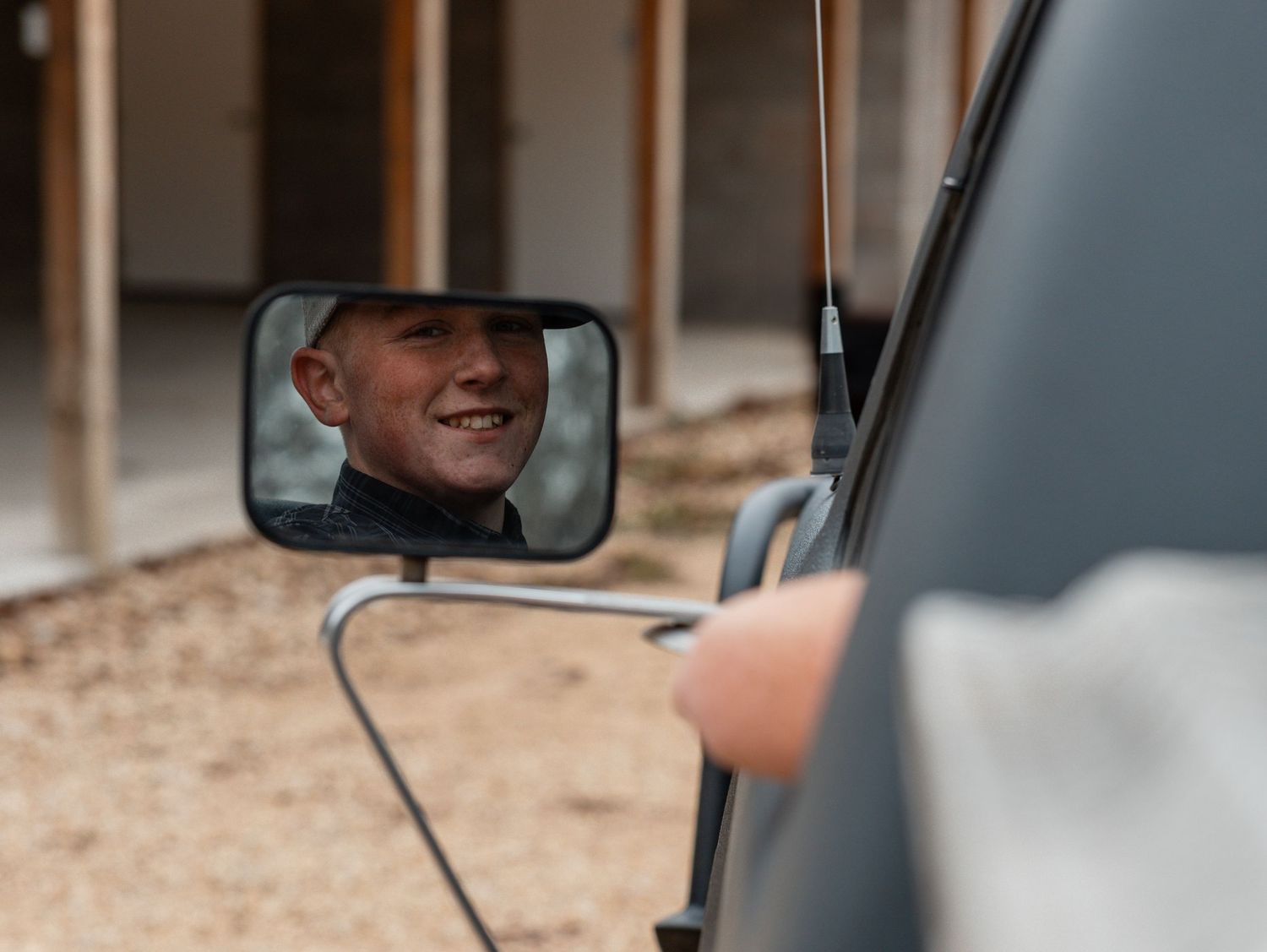 A person adjusts their rearview mirror while sitting in a car.