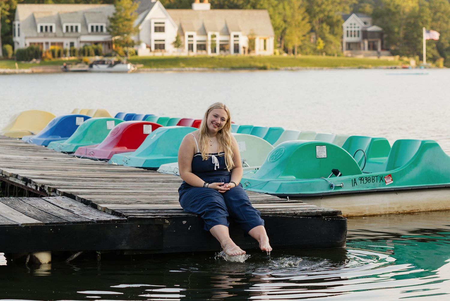 A row of colorful pedal boats docked at a lake pier on a sunny autumn day.