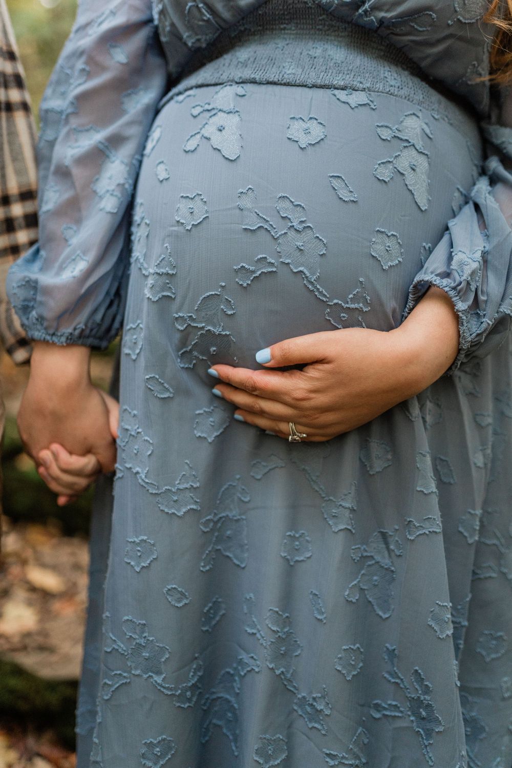 Close-up view of a blue-gray maternity dress with delicate floral embroidery details.