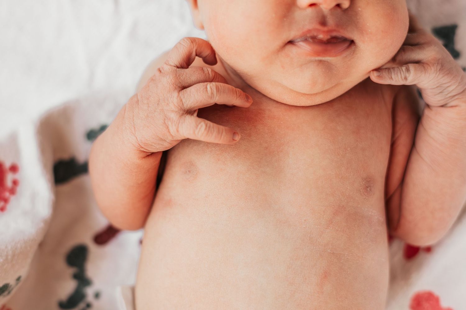 Close-up of a newborn baby lying on a floral blanket, showing chubby cheeks and tiny hands | Fresh 48 Hour Photos