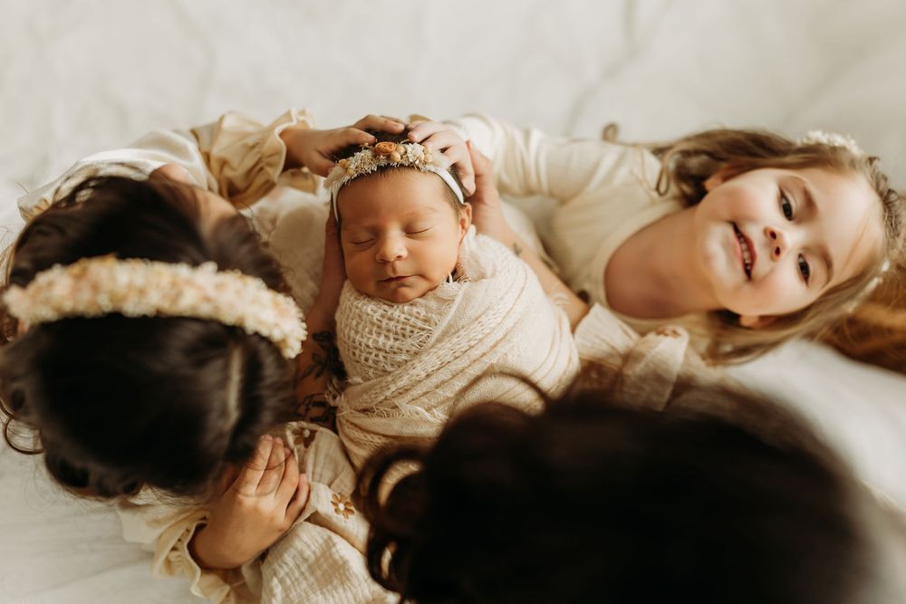 A sleeping newborn baby wrapped in soft white fabric against a neutral backdrop.