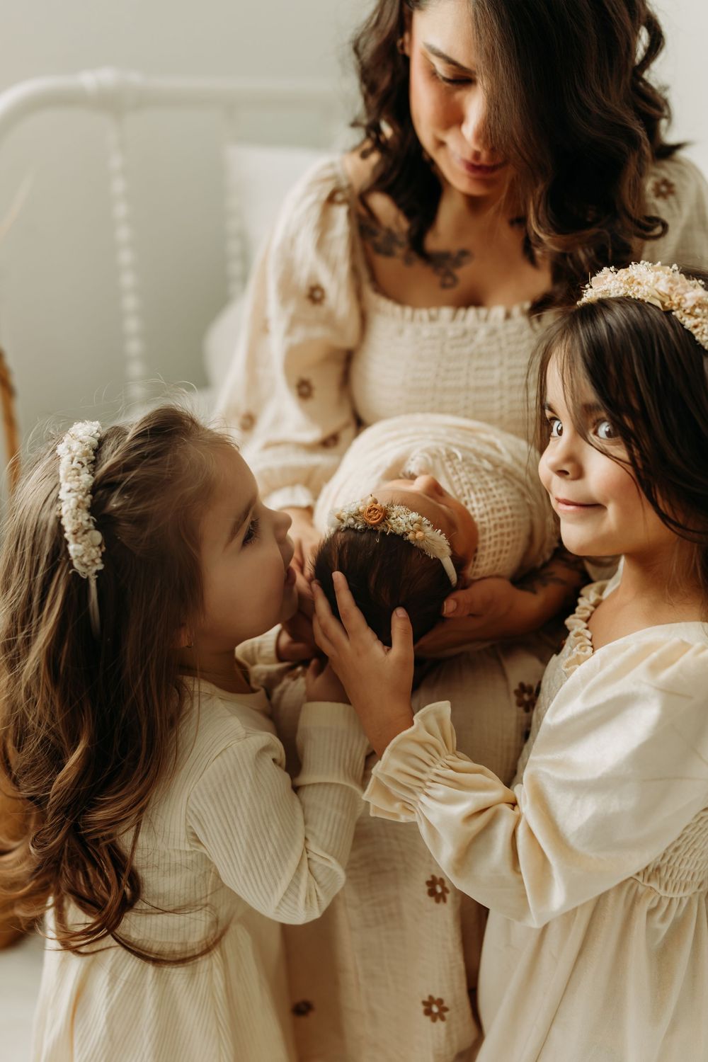 Two young children in white dresses sharing a sweet moment together.