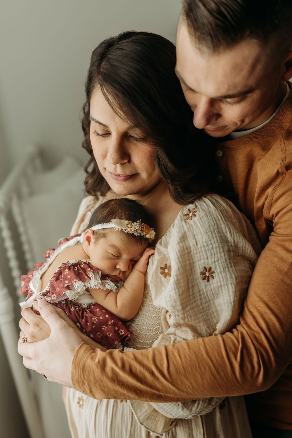 A series of intimate family moments showing parents cradling their newborn baby in warm, gentle poses.