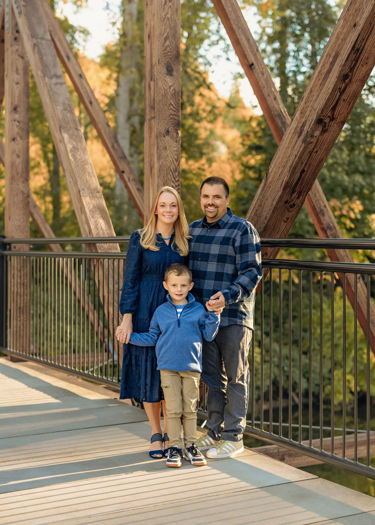 A family walks together on a rustic wooden bridge during golden hour in a park setting.