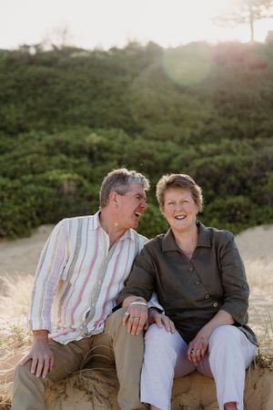 Two people share a heartfelt moment while sitting together on a coastal outcrop.