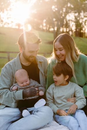 Family shares intimate moment together on blanket during sunset.