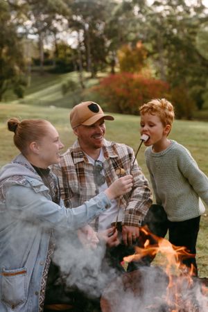 Family roasting marshmallows and laughing together around a campfire.