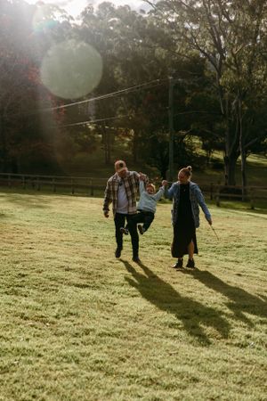 Family playing and walking together in a sunlit field during golden hour.