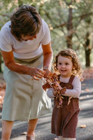 Adult and child looking at autumn leaves together on a path.