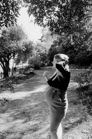 Black and white silhouette of pregnant woman standing on nature path.
