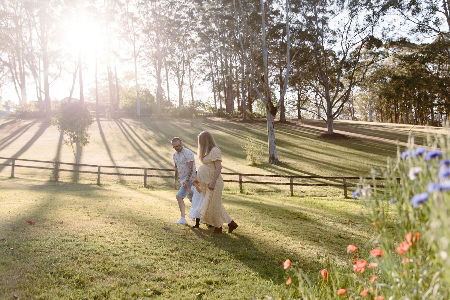 Family walking together on grassy hillside during golden sunset.
