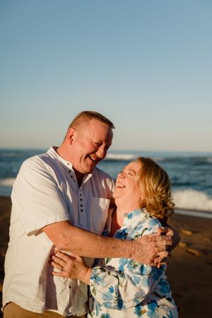 Couple sharing genuine laughter together on beach at sunset.