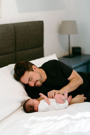 Tender parenting moment captured on white bedding in modern bedroom.