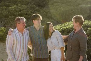 Four people in casual attire share a candid moment of laughter outdoors during golden hour.