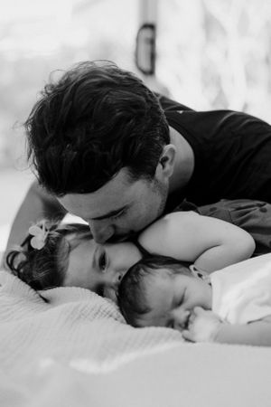 Sweet family moment captured in black and white as they cuddle together on bed.