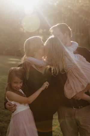Family sharing loving embrace in warm sunset light outdoors.