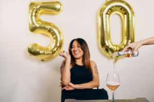 Celebration scene with large gold number balloons and champagne glasses.