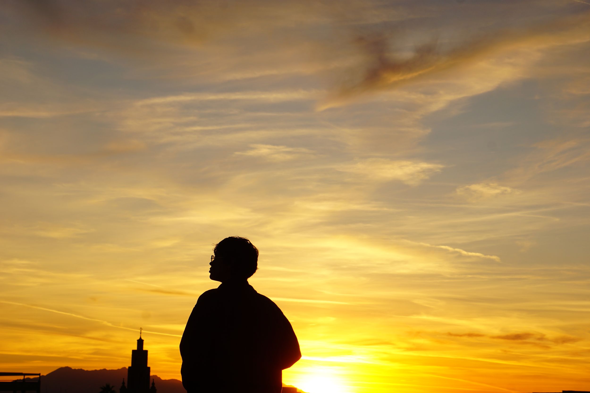 Dramatic sunset skyline with silhouettes against an orange and yellow sky.
