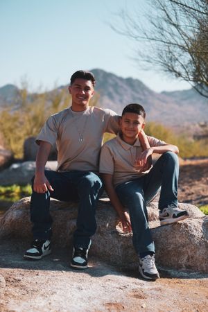 People sitting casually on desert rocks with mountains in the background.