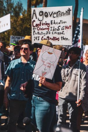Protesters holding signs at a demonstration about government and education issues.