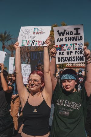 Crowd of protesters holding up handwritten signs during an outdoor demonstration.