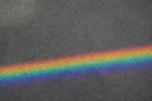 Spectrum of rainbow colors projected across a gray textured surface.