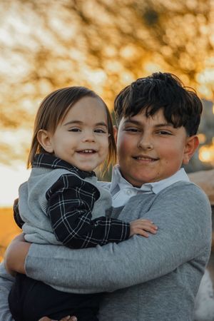 Two children hugging and laughing together during golden hour sunset.