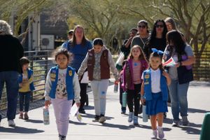 Group of students walking together on a sunny campus pathway.