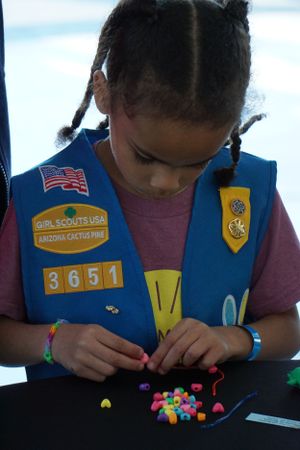 Girl scout working with colorful beads during an activity session.