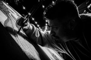 Dramatic black and white photo of someone drawing or writing in low light.