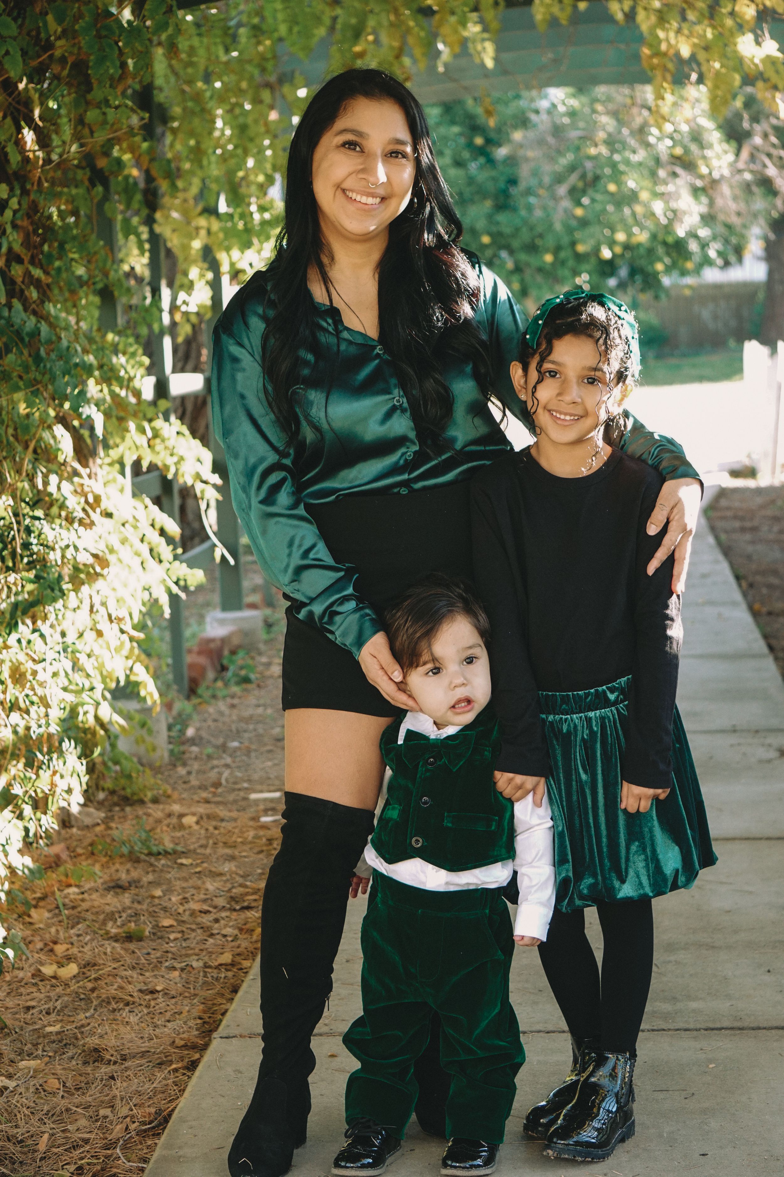 Family wearing coordinated emerald green velvet outfits posing outdoors.