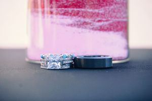 Close-up of an engagement ring with soft pink background lighting.