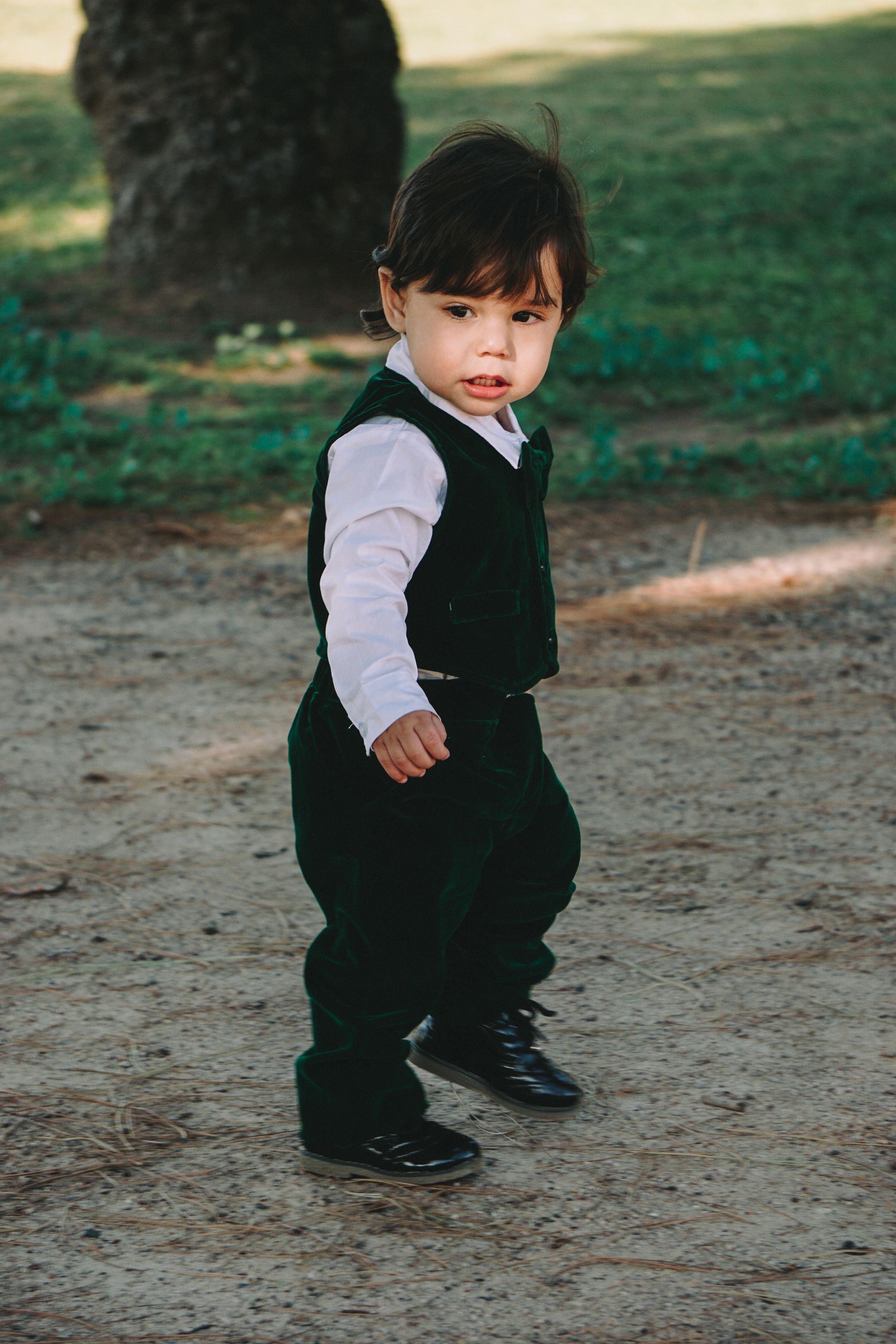 Small child in formal black and white outfit walking outdoors.