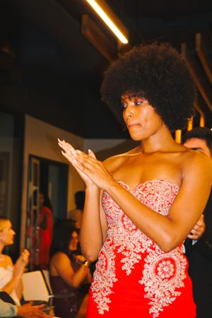 Woman in a red and white lace dress dancing expressively at an event.