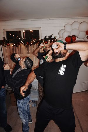Group of people doing shots at a party with string lights in the background.