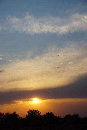 Panoramic sunset sky with golden clouds and sun on the horizon.